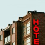Brick hotel building with bold red signage in Montreal, Canada, under a clear sky.