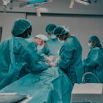 Medical professionals in scrubs conduct surgery in a hospital operating room.